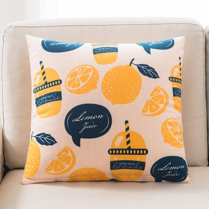 Decorative pillow with lemon and juice theme on a beige couch
