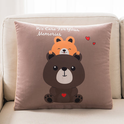 Decorative pillow with cartoon bear and fox design on a beige couch.