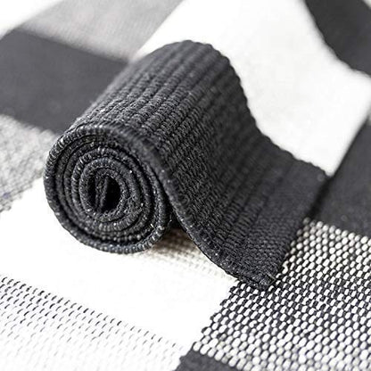 Portland cotton buffalo check runner rug rolled to show flat-weave construction and non-slip mesh backing — black and white, Studio Reign