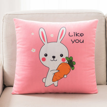 Pink pillow with a cartoon bunny holding a carrot and the text 'Like you' on a beige couch.